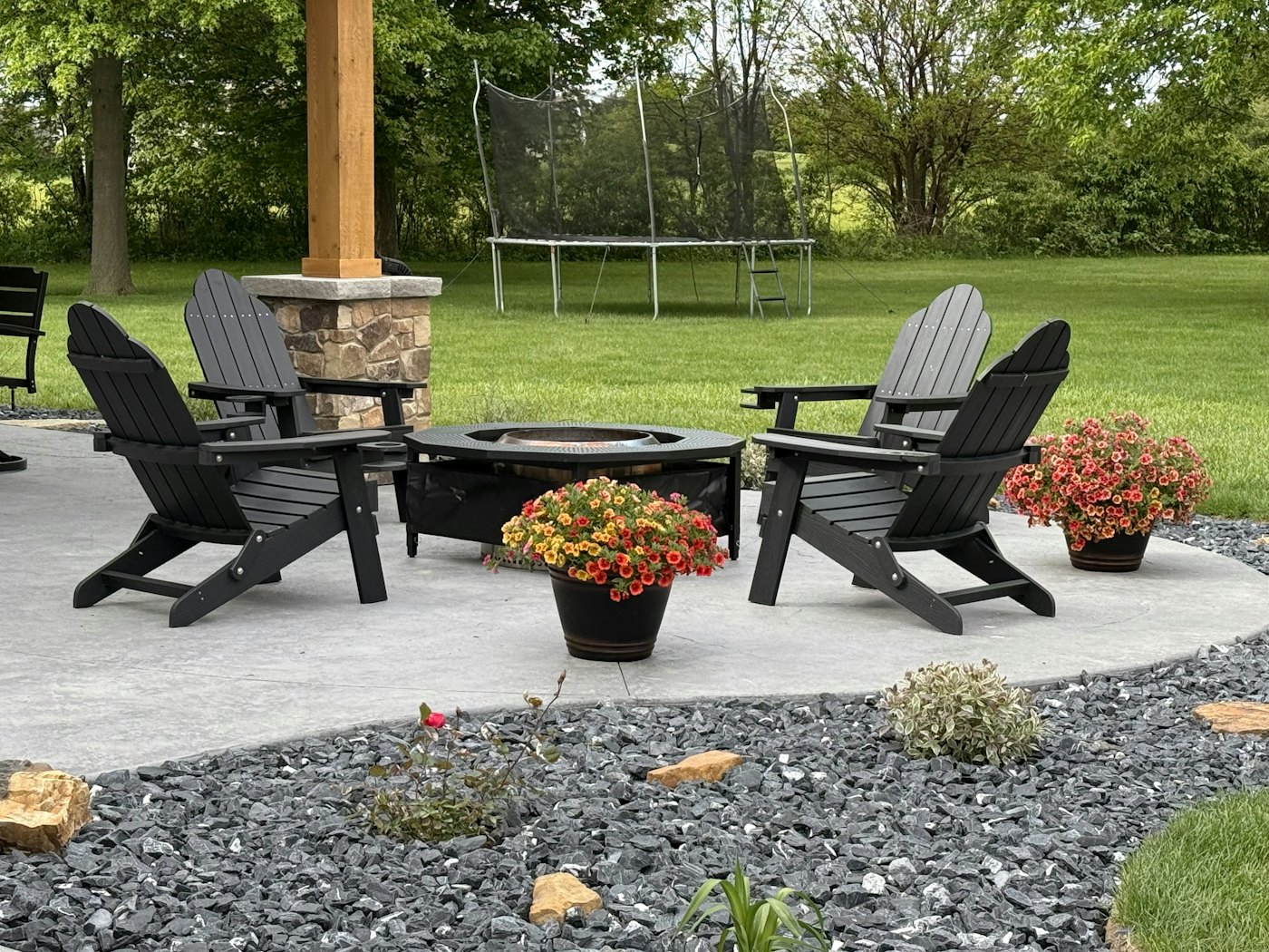 A paver patio with a fire pit, seat wall and adirondack chairs